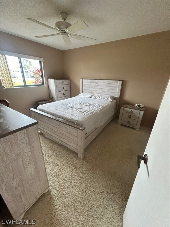 carpeted bedroom with a textured ceiling and ceiling fan