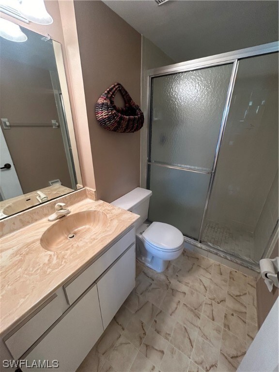 bathroom featuring large vanity, a shower with door, tile flooring, and toilet