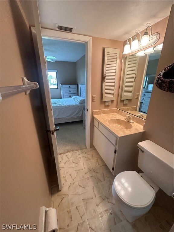 bathroom with toilet, large vanity, and tile flooring