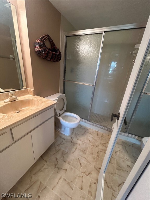 bathroom with toilet, a shower with door, tile floors, and oversized vanity