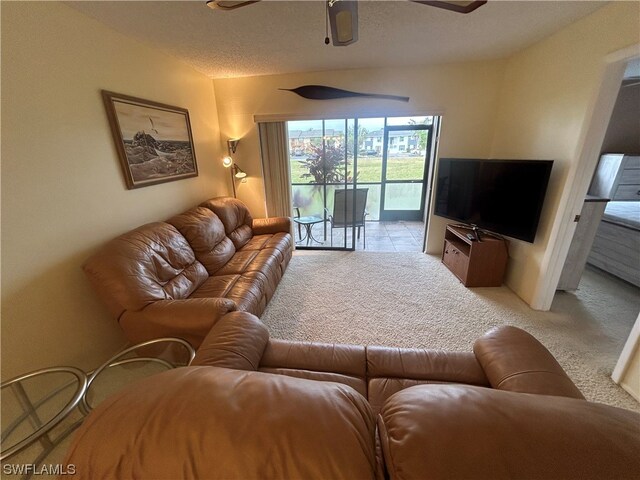 carpeted living room with a textured ceiling and ceiling fan