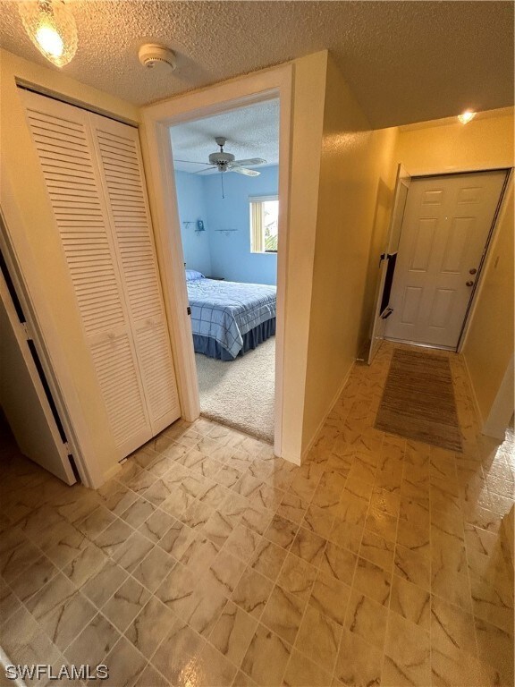 hallway with light tile floors and a textured ceiling