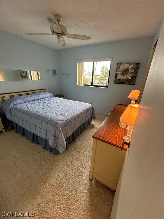 carpeted bedroom with ceiling fan and a textured ceiling