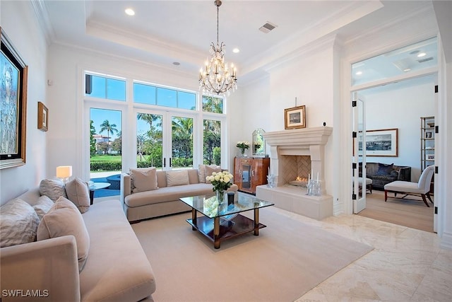 living area with visible vents, a lit fireplace, ornamental molding, french doors, and a raised ceiling
