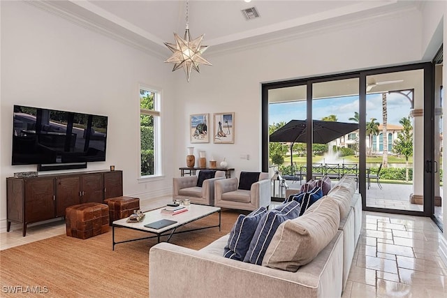 living room with baseboards, visible vents, stone tile flooring, crown molding, and a chandelier