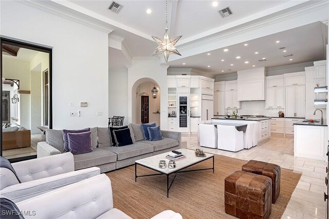 living area featuring arched walkways, visible vents, recessed lighting, and crown molding