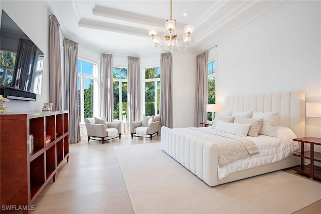 bedroom with a tray ceiling, wood finished floors, crown molding, and a chandelier