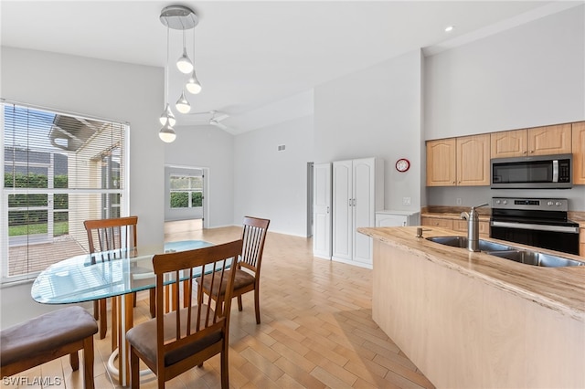 dining room with high vaulted ceiling, light wood-type flooring, and sink