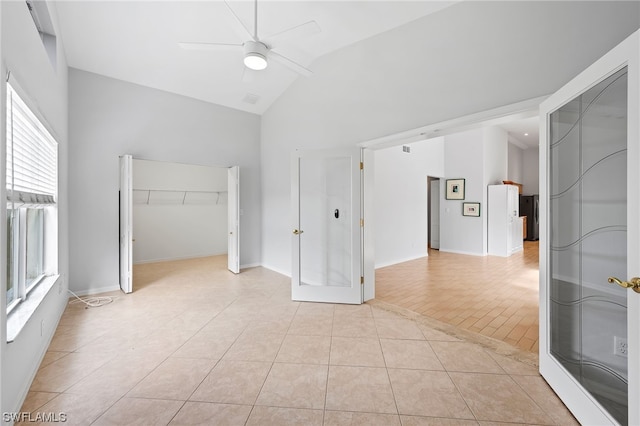 tiled spare room featuring lofted ceiling, ceiling fan, and a healthy amount of sunlight