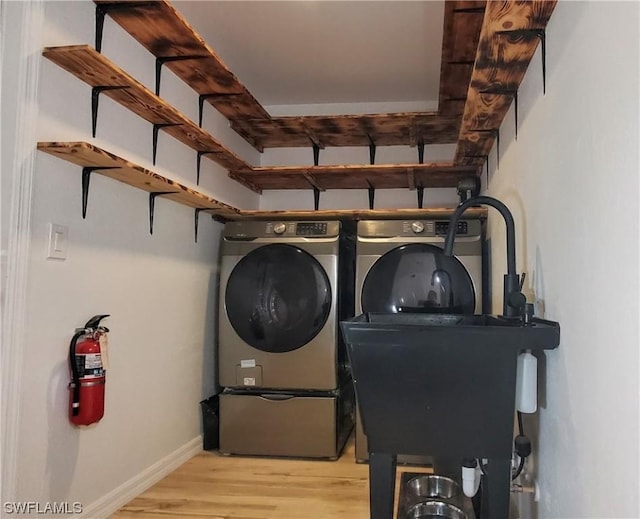 clothes washing area featuring light hardwood / wood-style flooring and washing machine and dryer