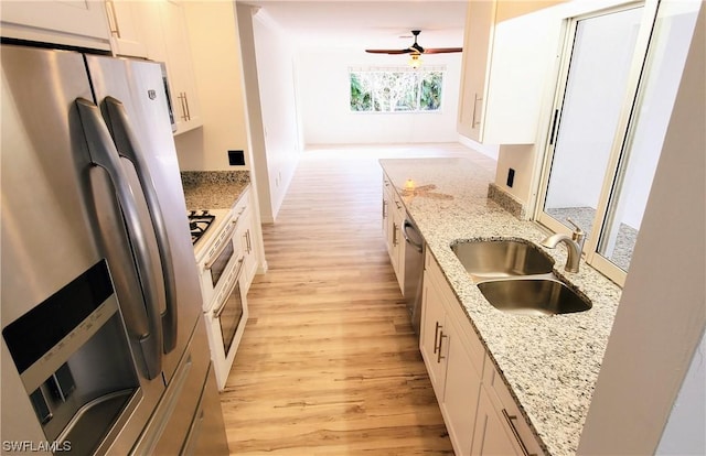 kitchen with white cabinetry, sink, stainless steel appliances, and light stone countertops