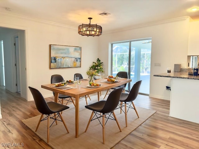 dining area featuring an inviting chandelier, crown molding, and light wood-type flooring