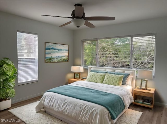 bedroom with multiple windows, wood-type flooring, and ceiling fan