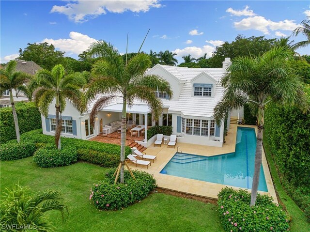 back of property featuring outdoor lounge area, a patio area, and a lawn