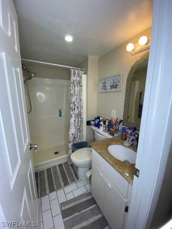 bathroom featuring tile patterned flooring, a shower with curtain, vanity, and toilet