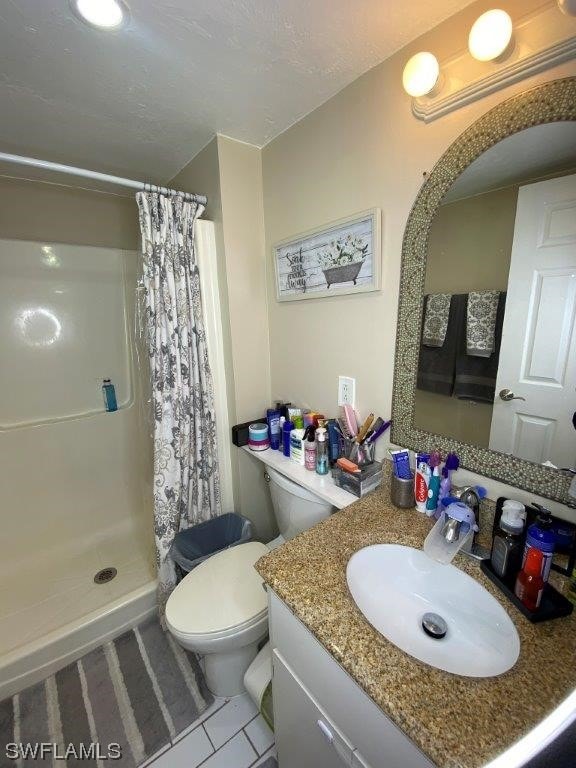 bathroom featuring curtained shower, tile patterned flooring, vanity, and toilet