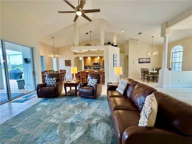 tiled living room with high vaulted ceiling, ceiling fan with notable chandelier, and ornate columns