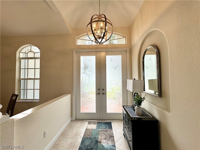 tiled entryway featuring vaulted ceiling, french doors, and an inviting chandelier