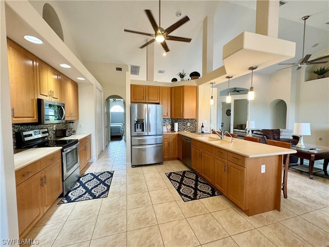 kitchen with tasteful backsplash, stainless steel appliances, ceiling fan, and high vaulted ceiling