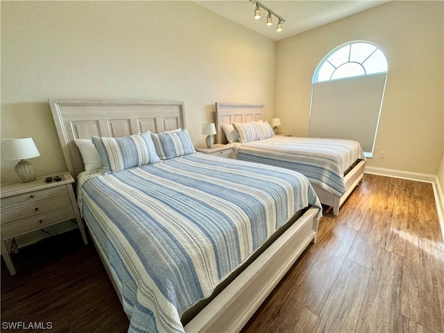 bedroom featuring rail lighting and dark hardwood / wood-style floors