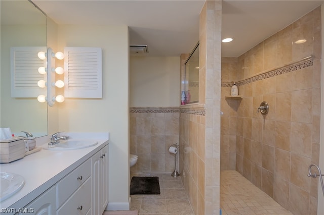 bathroom with a tile shower, tile flooring, toilet, and dual bowl vanity