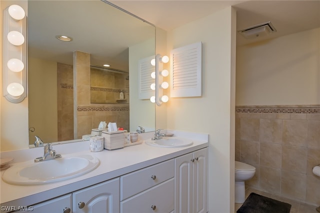 bathroom with tile walls, toilet, dual bowl vanity, and tile flooring