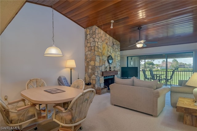 carpeted dining room featuring high vaulted ceiling, a stone fireplace, ceiling fan, and wood ceiling