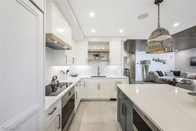 kitchen with pendant lighting, wall oven, black electric stovetop, white cabinets, and backsplash