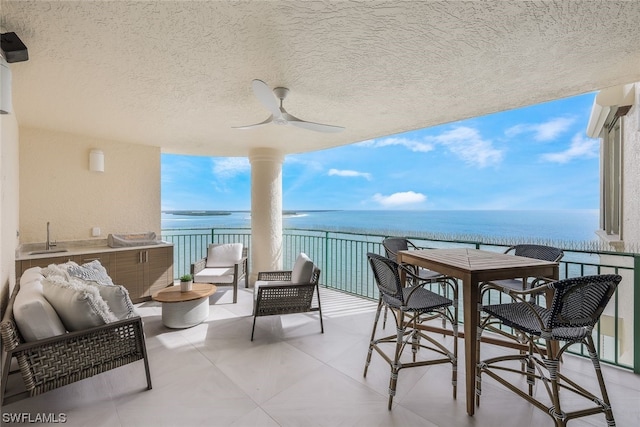 balcony with outdoor lounge area, ceiling fan, and a water view