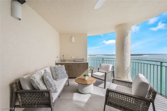 balcony featuring an outdoor living space, sink, and a water view