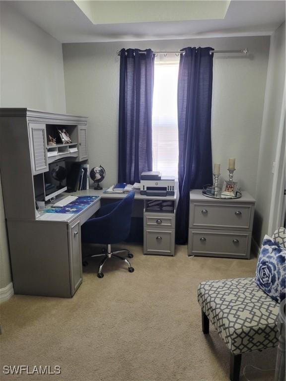 carpeted home office with a raised ceiling