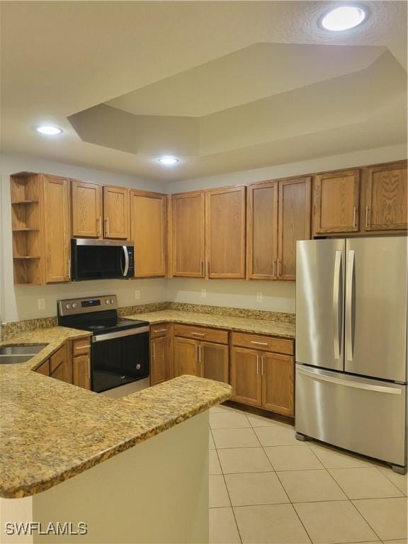 kitchen featuring kitchen peninsula, appliances with stainless steel finishes, a raised ceiling, sink, and light tile patterned floors