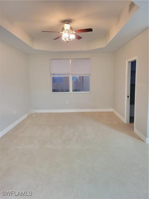 carpeted empty room featuring a tray ceiling and ceiling fan