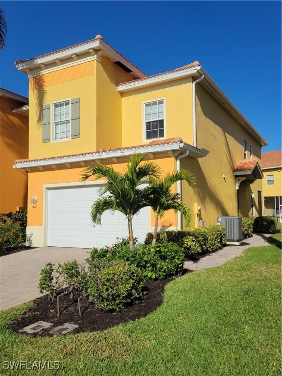 view of front facade featuring a garage, central air condition unit, and a front yard