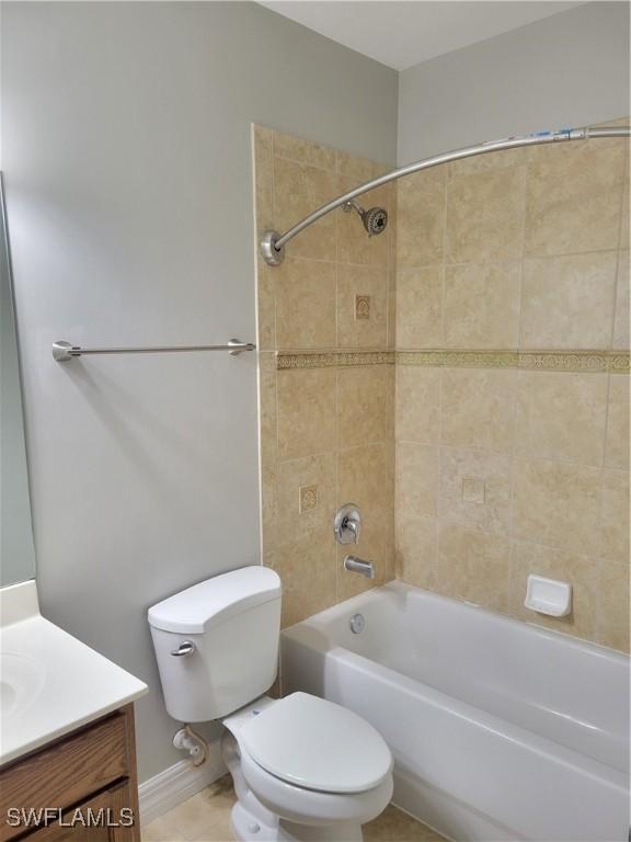 full bathroom with tiled shower / bath, tile patterned flooring, vanity, and toilet