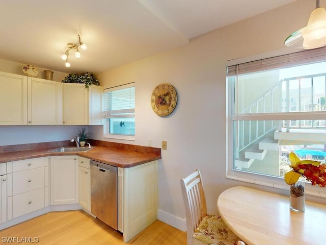 kitchen with stainless steel dishwasher, light hardwood / wood-style flooring, white cabinetry, hanging light fixtures, and sink