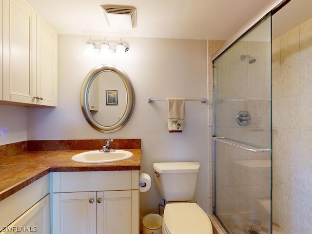 bathroom with toilet, a shower with shower door, and large vanity