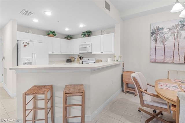 kitchen featuring a breakfast bar, light tile patterned floors, light countertops, visible vents, and white appliances