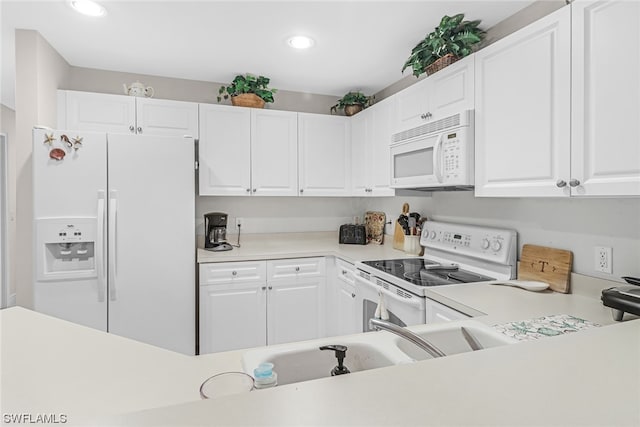 kitchen featuring white appliances, white cabinets, light countertops, and recessed lighting