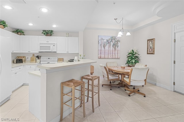 kitchen with a breakfast bar, white appliances, white cabinetry, and light tile patterned floors