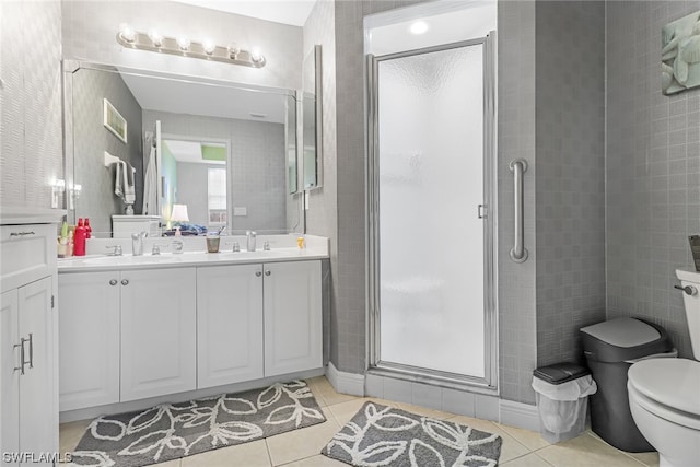 full bath featuring double vanity, a shower stall, toilet, and tile patterned floors