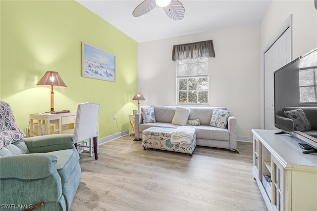 living area with light wood-style floors, baseboards, and a ceiling fan