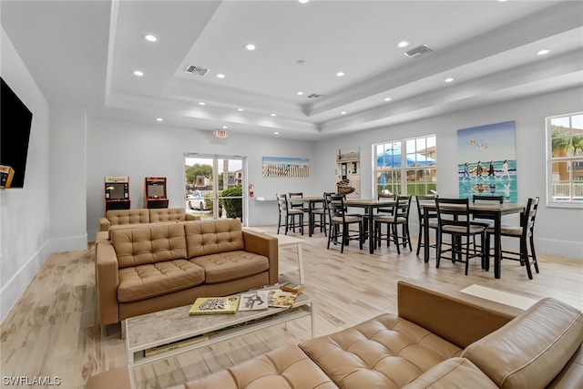 living area featuring a wealth of natural light, a tray ceiling, and visible vents