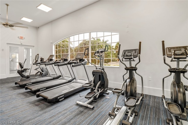 workout area featuring carpet flooring, ceiling fan, a towering ceiling, and baseboards