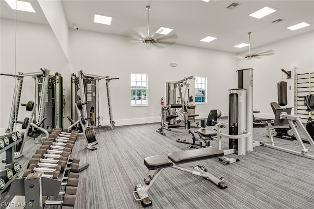 exercise room with a towering ceiling, ceiling fan, visible vents, and carpet flooring