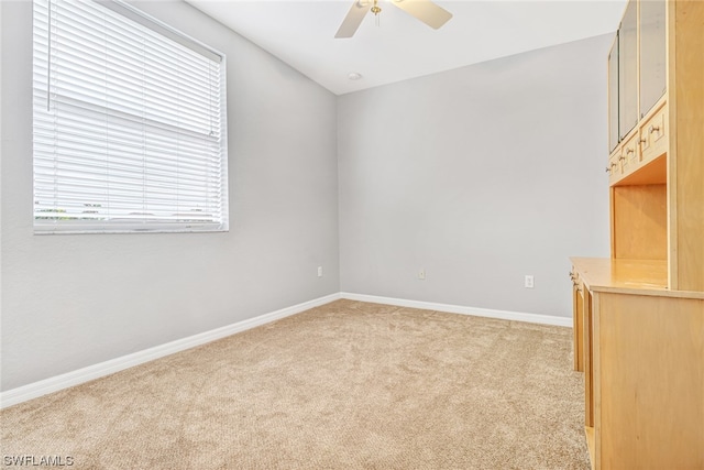 empty room with ceiling fan and light carpet