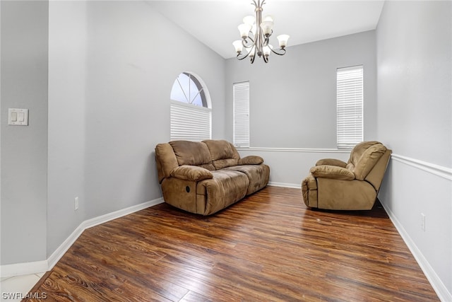 sitting room with lofted ceiling, an inviting chandelier, and dark wood-type flooring