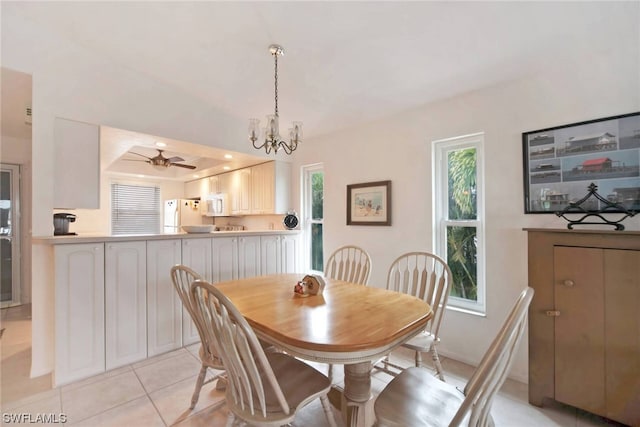 tiled dining room with a raised ceiling and ceiling fan with notable chandelier