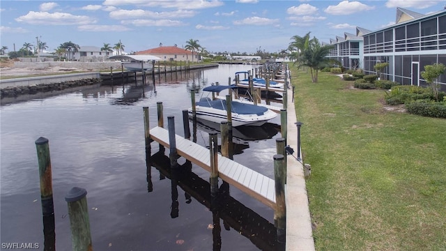 view of dock with a lawn and a water view