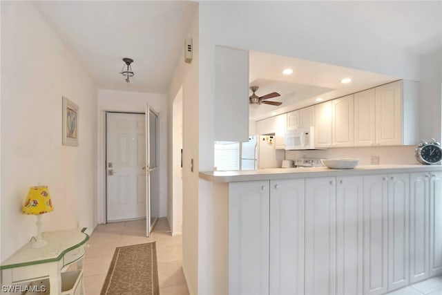 kitchen featuring white cabinetry, a tray ceiling, ceiling fan, white appliances, and light tile floors